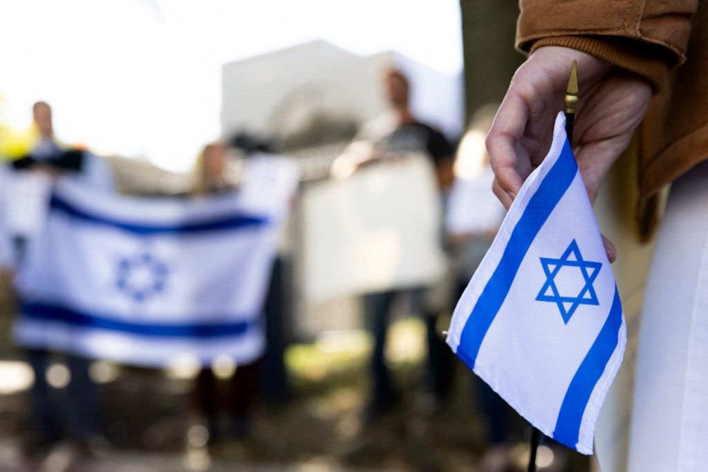 A supporter of Israel holds an Israeli flag in front of the Israeli Embassy in Washington, DC, on October 8, 2023 after the Palestinian militant group Hamas launched an assault on Israel. Israel, reeling from the deadliest attack on its territory in half a century, formally declared war on Hamas Sunday as the conflict's death toll surged close to 1,000 after the Palestinian militant group launched a massive surprise assault from Gaza. (Photo by Julia Nikhinson / AFP)