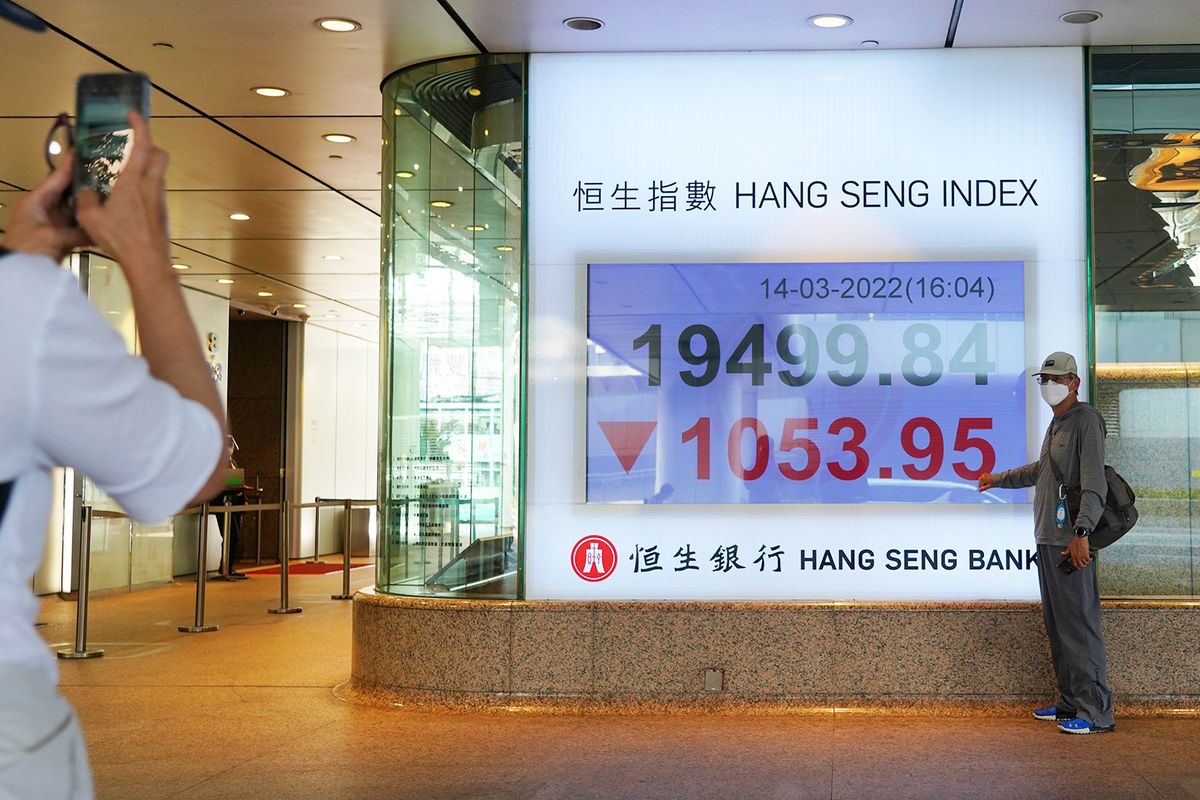 HONG KONG, CHINA - MARCH 14: A pedestrian poses for a photo in front of an electronic screen displaying the Hang Seng Index at Hang Seng Bank on March 14, 2022 in Hong Kong, China. (Photo by Zhang Wei/China News Service via Getty Images)