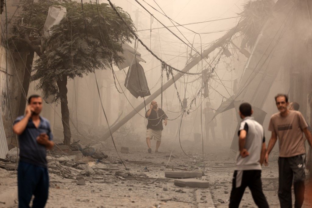 TOPSHOT - Palestinians inspect the destruction in a neighbourhood heavily damaged by Israeli airstrikes on Gaza City's Shati refugee camp early on October 9, 2023. The Israeli army said it hit more than 500 targets in the Gaza Strip in overnight strikes, as the death toll from its war with Palestinian militants surged above 1,100. (Photo by MAHMUD HAMS / AFP)