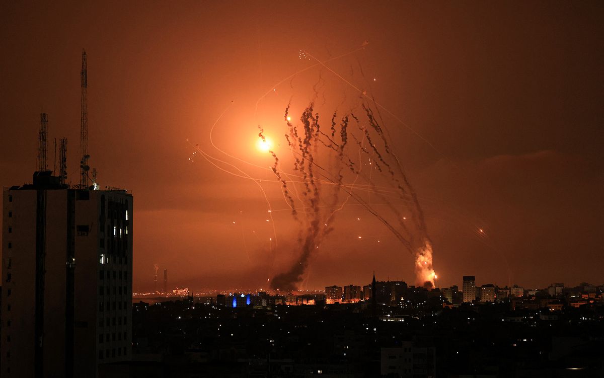 A salvo of rockets is fired by Palestinian militants from Gaza as an Israeli missile launched from the Iron Dome defence missile system attempts to intercept the rockets, fired from the Gaza Strip, over the city of Netivot in southern Israel on October 8, 2023. Israel, reeling from the deadliest attack on its territory in half a century, formally declared war on Hamas Sunday as the conflict's death toll surged close to 1,000 after the Palestinian militant group launched a massive surprise assault from Gaza. (Photo by MAHMUD HAMS / AFP)