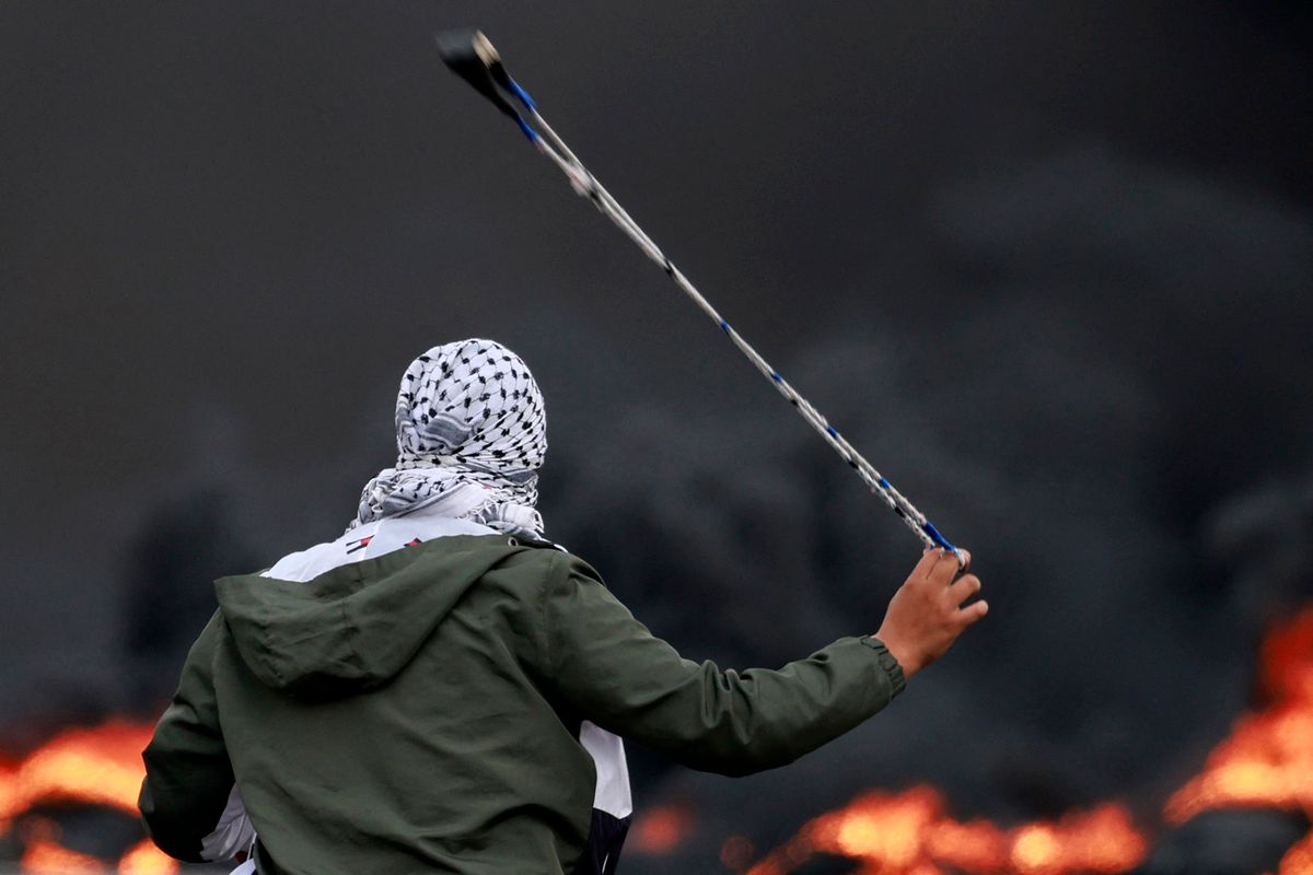 A Palestinian hurls stones at Israeli forces during a demonstration against Israli bombardment of the Gaza strip, in the city of Ramallah in the occupied West Bank on October 11, 2023. Thousands have died and the toll continues to climb dramatically five days after Palestinian militants launched a surprise attack on Israel, which has responded with a massive bombardment of Gaza. (Photo by Jaafar ASHTIYEH / AFP)