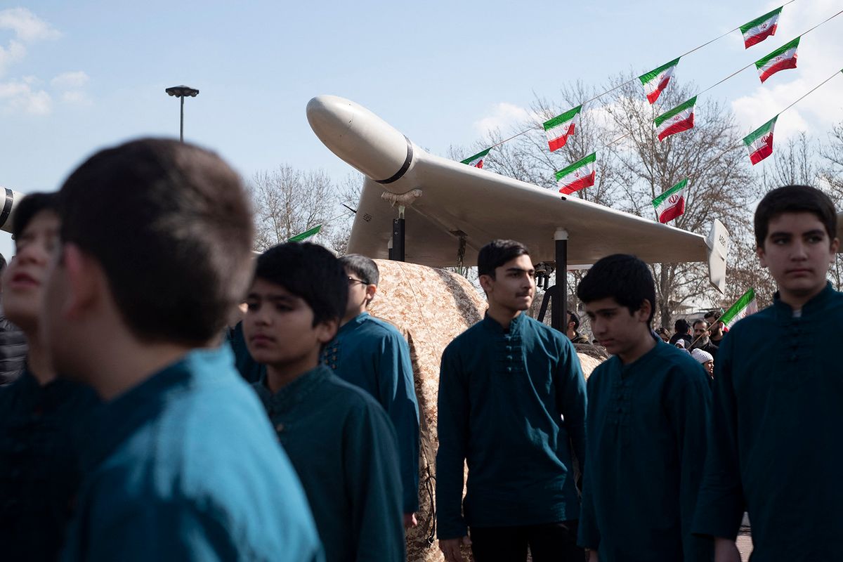 Iranian youth are standing under an Iranian-made unmanned aerial vehicle (UAV) Shahed-136, during a rally to mark the 44th anniversary of the Victory of Iran's 1979 Islamic Revolution, at Azadi (Freedom) Square in the west of Tehran on February 11, 2023. (Photo by Morteza Nikoubazl/NurPhoto) (Photo by Morteza Nikoubazl / NurPhoto / NurPhoto via AFP)