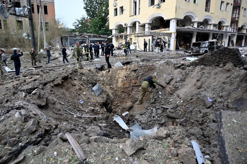 An expert examines a crater after a Russian strike to the centre of the Ukrainian city of Kharkiv on October 6, 2023, amid Russian invasion in Ukraine. At least sixteen people were wounded and a child reported dead after a Russian strike on Kharkiv, said the Ukrainian Interior Minister on October 6, 2023. (Photo by SERGEY BOBOK / AFP)