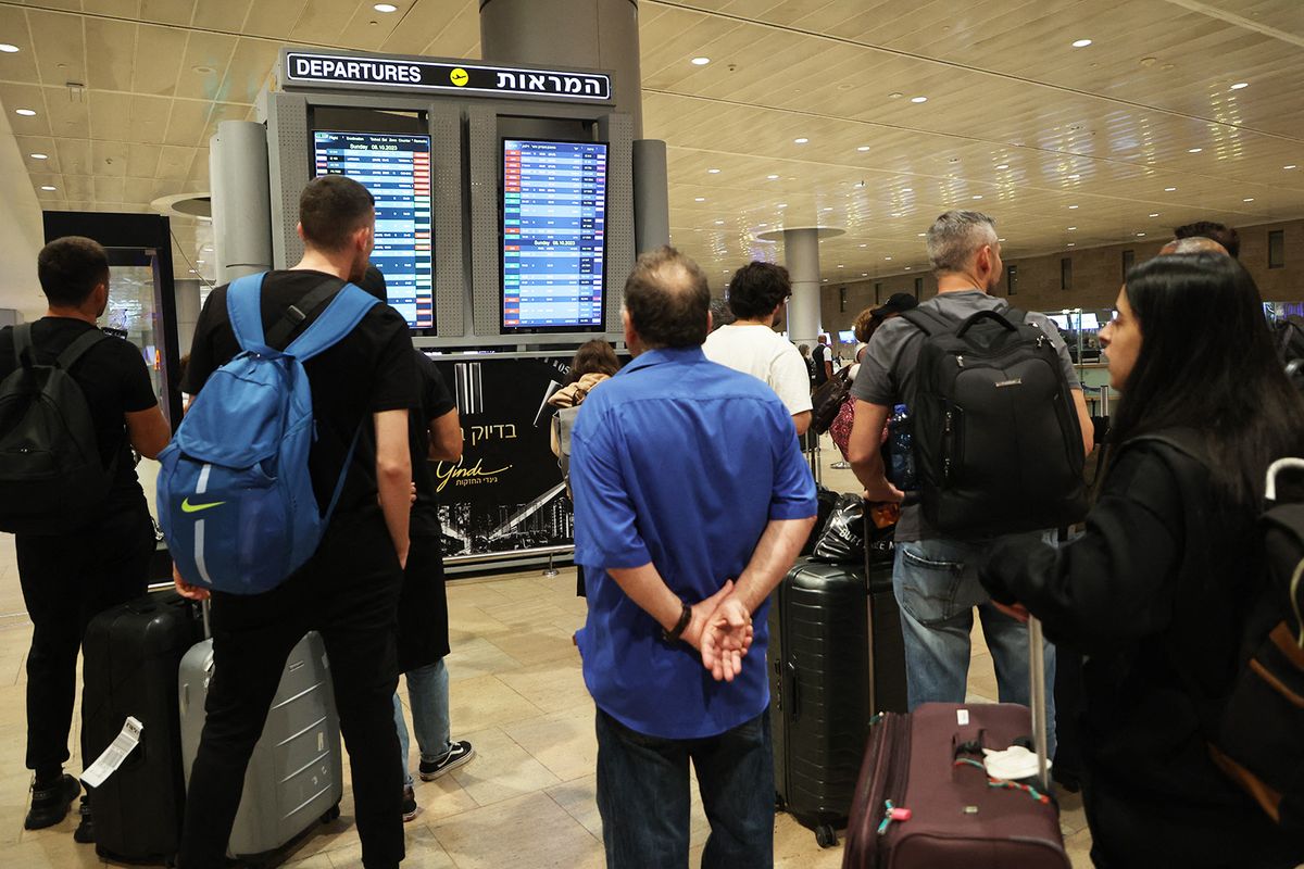 Passengers look at a departure board at Ben Gurion Airport near Tel Aviv, Israel, on October 7, 2023, as flights are canceled because of the Hamas surprise attacks. The conflict sparked major disruption at Tel Aviv airport, with American Airlines, Emirates, Lufthansa and Ryanair among carriers with cancelled flights. (Photo by GIL COHEN-MAGEN / AFP)
