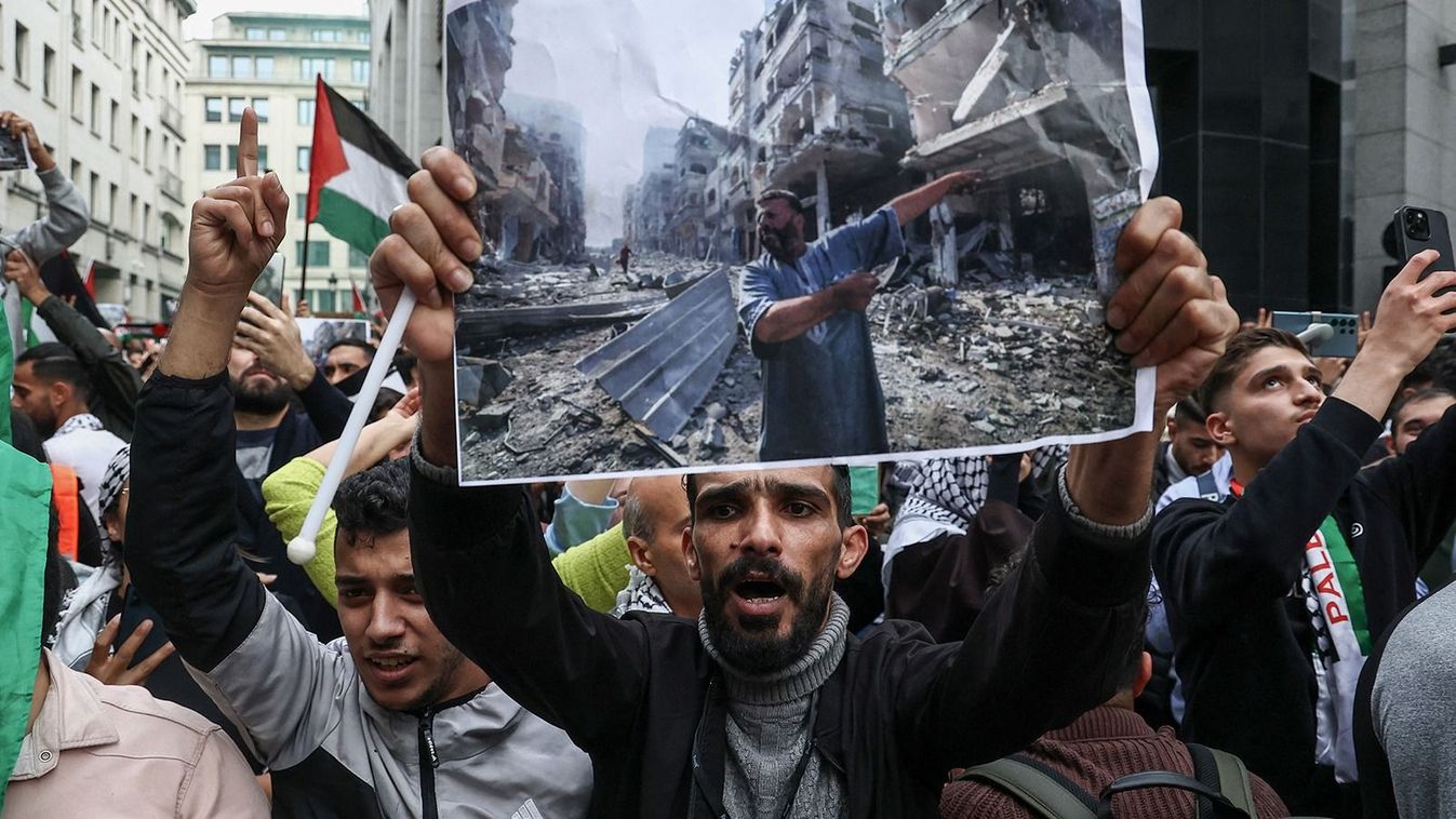 A protester holds a photograph taken by AFP photographer Mahmud Hams (of people inspecting the damage following an overnight Israeli airstrikes in the Gaza Strip) above his head during a demonstration against Israel's military operations in Gaza and in support of Palestinians, in Brussels on October 11, 2023. (Photo by Kenzo TRIBOUILLARD / AFP)