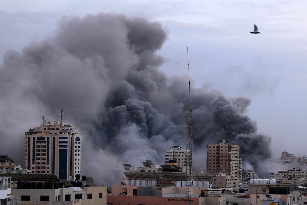 A black plume of smoke billows behind highrise buildings during an Israeli airstrike on Gaza City on October 9, 2023. Israel relentlessly pounded the Gaza Strip overnight and into October 9 as fighting with Hamas continued around the Gaza Strip, as the death toll from the war against the Palestinian militants surged above 1,100. (Photo by MAHMUD HAMS / AFP)