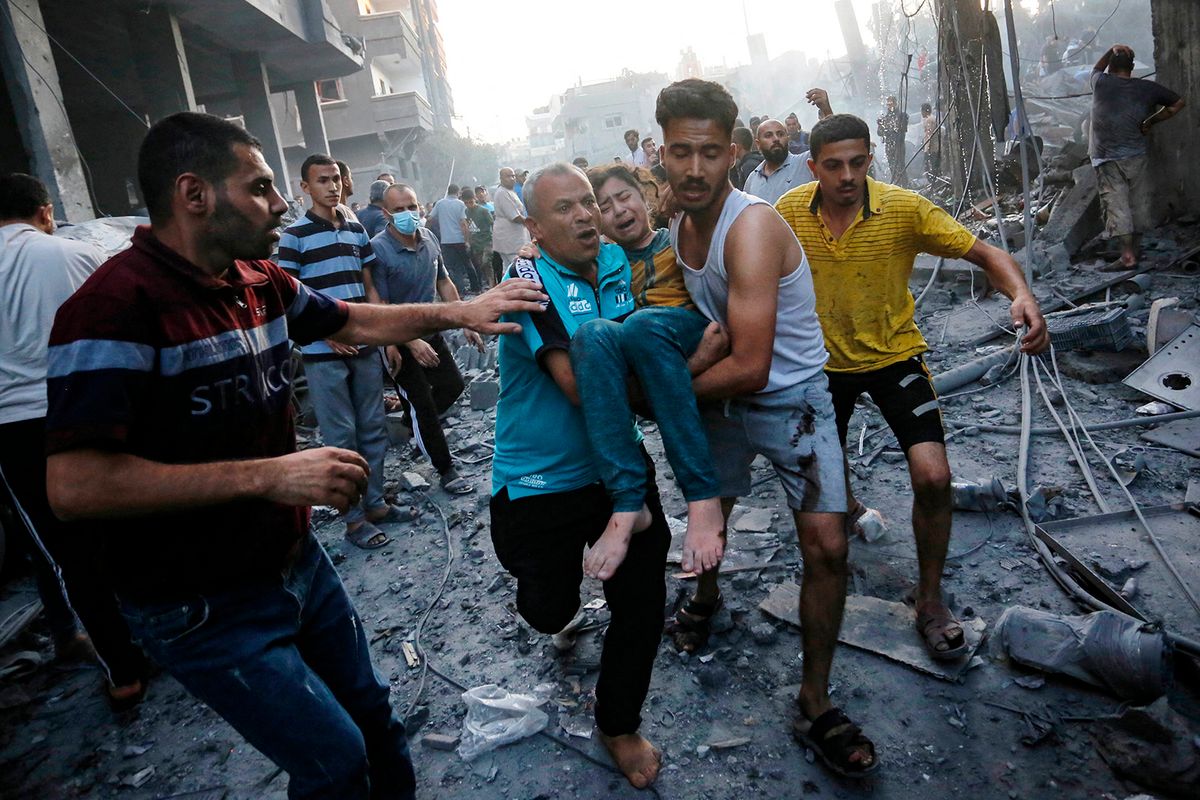 EDITORS NOTE: Graphic content / Men carry away an injured girl following an Israeli strike on the town of Deir Al-Balah in the central Gaza Strip on October 18 2023. Thousands of people, both Israeli and Palestinians have died since October 7, 2023, after Palestinian Hamas militants based in the Gaza Strip, entered southern Israel in a surprise attack leading Israel to declare war on Hamas in Gaza on October 8. (Photo by Mohammed Faiq / AFP)