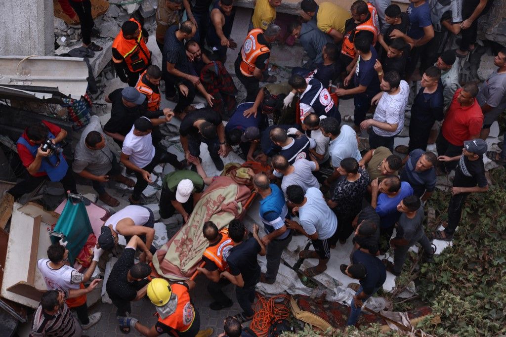 Rescuers remove people from under the rubble of a house destroyed by an Israeli air strike in Rafah in the southern Gaza Strip, on October 9, 2023. The Israeli army said it hit more than 500 targets in the Gaza Strip in overnight strikes, as the death toll from its war with Palestinian militants surged above 1,100. (Photo by SAID KHATIB / AFP)