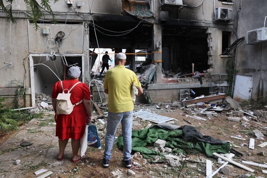 Residents inspect the damage to their building in the southern city of Ashkelon on October 9, 2023, after it was hit during the night by a rocket from the Gaza Strip. Israel relentlessly pounded the Gaza Strip overnight and into October 9 as fighting with Hamas continued around the Gaza Strip, as the death toll from the war against the Palestinian militants surged above 1,100. (Photo by Menahem KAHANA / AFP)