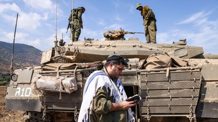 EDITORS NOTE: Graphic content / An Israeli sodleir prays standing in front of a Merkava tank on the outskirts of the northern town of Kiryat Shmona near the border with Lebanon on October 8, 2023. Lebanon's Hezbollah and Israel said they traded cross-border fire on October 8, as Israel fought the Shiite movement's ally Hamas on its southern flank a day after militants from the Palestinian group stormed its Gaza frontier. (Photo by JALAA MAREY / AFP)