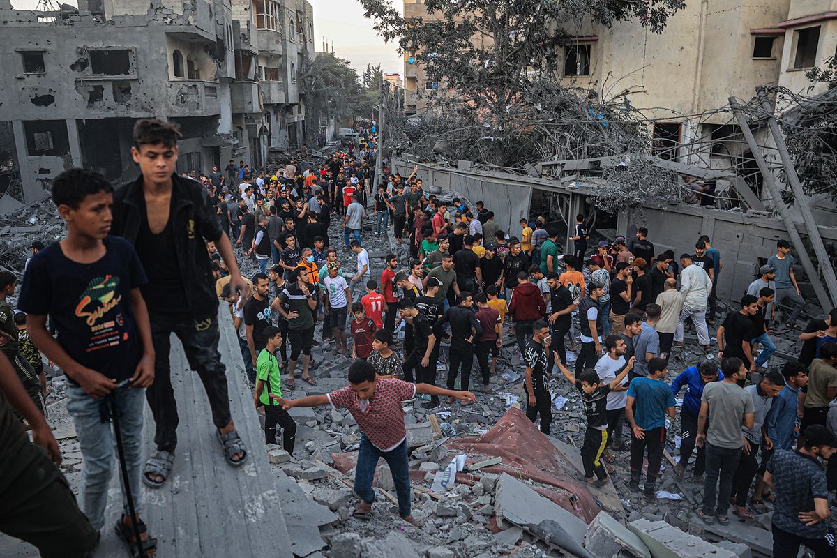 People gather in a neighbourhood in Rafah in the southern Gaza Strip, after it was hit by an Israeli strike on October 15, 2023. Israel embarked on a withering air campaign against Hamas militants in Gaza after they carried out a brutal attack on Israel on October 7 that left more than 1,400 people killed in Israel. (Photo by SAID KHATIB / AFP)