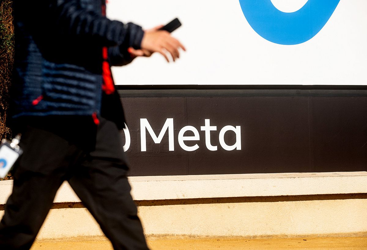 A person walks past a newly unveiled logo for "Meta", the new name for Facebook's parent company, outside Facebook headquarters in Menlo Park on October 28, 2021. Facebook changed its parent company name to "Meta" on October 28 as the tech giant tries to move past being a scandal-plagued social network to its virtual reality vision for the future. (Photo by NOAH BERGER / AFP)