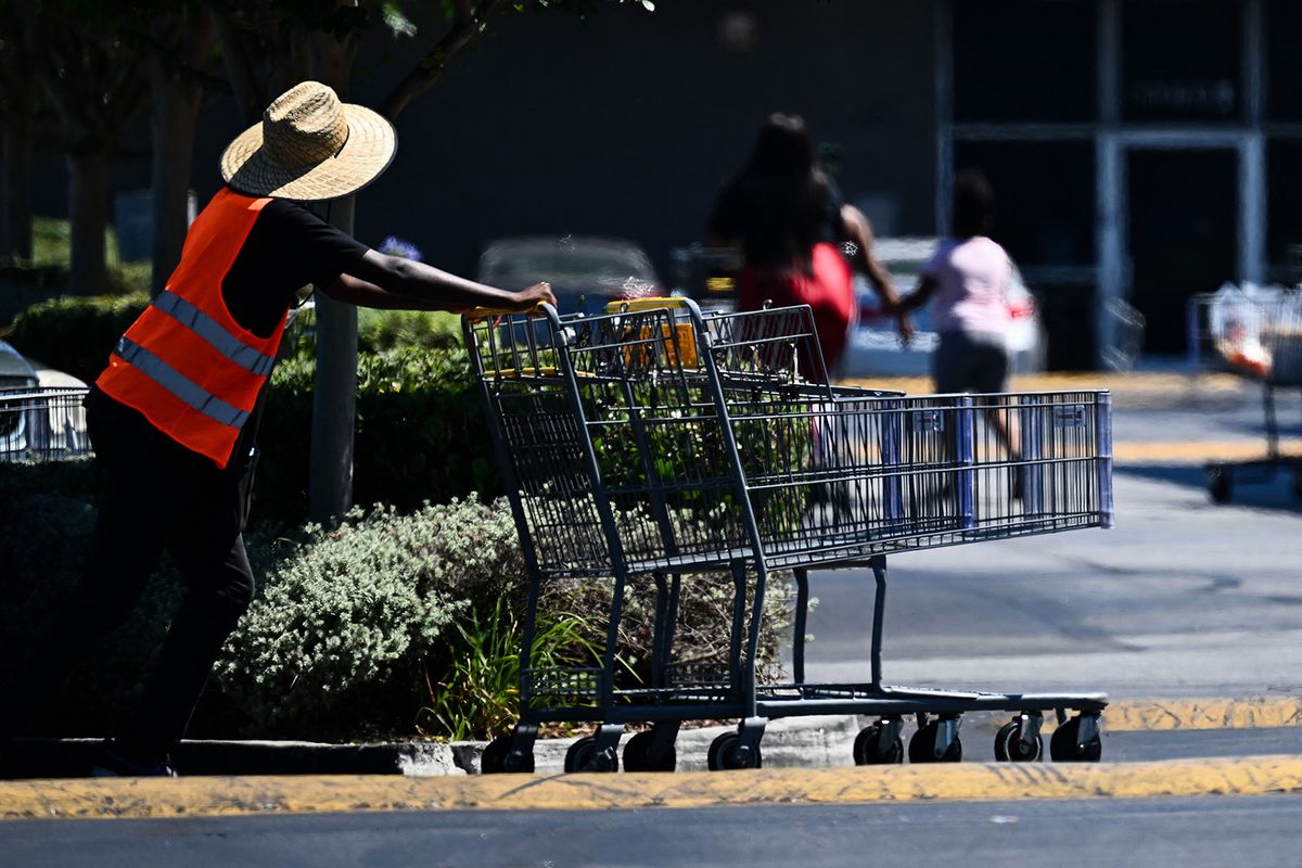 A grocery store worker wears a hat to protect their head from the sun while pushing shopping carts in a parking lot in Los Angeles, California on July 11, 2023. More than 50 million Americans are set to bake under dangerously high temperatures this week, from California to Texas to Florida, as a heat wave builds across the southern United States. (Photo by Patrick T. Fallon / AFP)