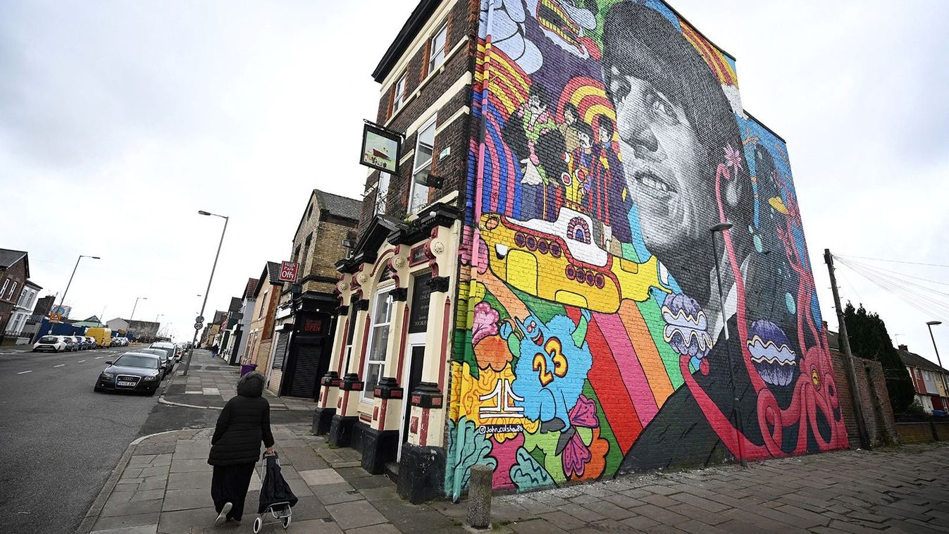 A pedestrian walks past a mural depicting former Beatles member Ringo Starr and painted by Liverpool artist John Culshaw, on the facade wall of The Empress Pub in Toxteth, Liverpool, north west England, on March 9, 2022. The mural has been painted close to places connected with the former Beatles including his birthplace and childhood home. (Photo by Paul ELLIS / AFP) / RESTRICTED TO EDITORIAL USE - MANDATORY MENTION OF THE ARTIST UPON PUBLICATION - TO ILLUSTRATE THE EVENT AS SPECIFIED IN THE CAPTION