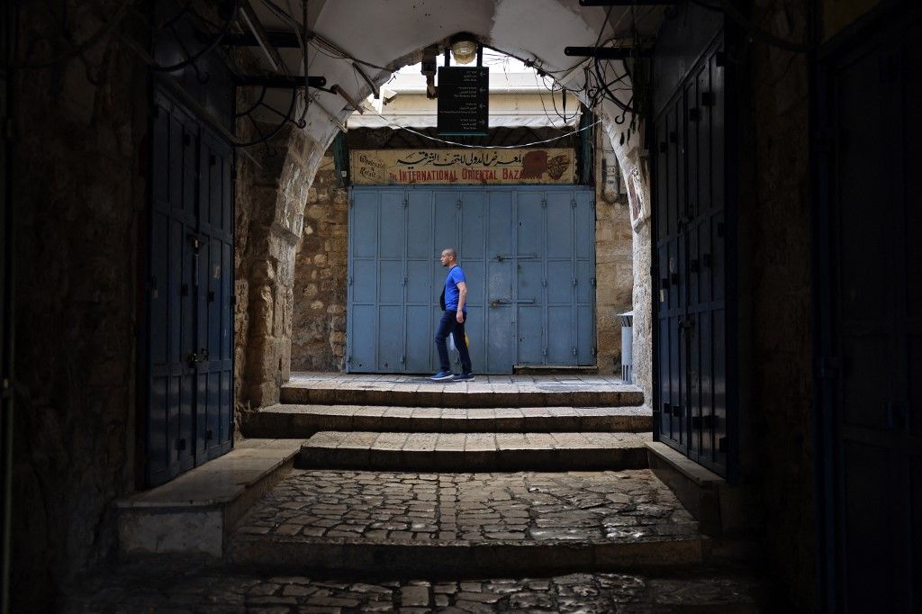 A man walks down a street past closed shops in the Christian quarter of the Jerusalem’s Old City, on October 16, 2023. Tourism has largely come to a standstill since fighting erupted week when Hamas militants launched a surprise attack on Israel, which has responded with a massive bombardment of Gaza. (Photo by Thomas COEX / AFP)