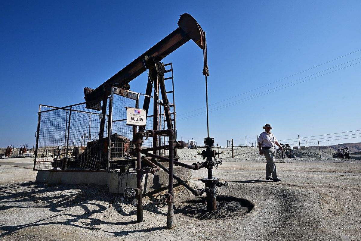 Third-generation oilman Fred Holmes walks past a working pumpjack at his oilfield in Taft, Kern County, California on September 21, 2023. California produces 311,000 barrels of crude oil every day, around 2.4 percent of all US production, making it the seventh largest producing state in the union. But it is also at the leading edge of environmentalism in the United States, and is determined to shrink its dependency. (Photo by Frederic J. BROWN / AFP)