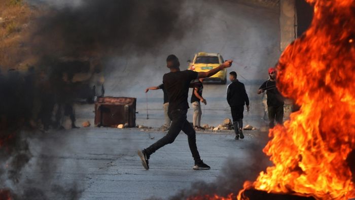 A Palestinian demonstrator throws rocks towards Israeli soldiers during clashes in the city of Ramallah in the occupied West Bank on October 8, 2023. Israel, reeling from the deadliest attack on its territory in half a century, formally declared war on Hamas on October 8, as the conflict's death toll surged to 1,000 after the Palestinian militant group launched a massive surprise assault from Gaza. (Photo by Jaafar ASHTIYEH / AFP)
