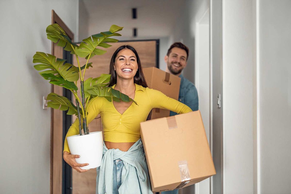Young,Couple,Moving,In,New,Home.couple,Is,Having,Fun,WithYoung couple moving in new home.Couple is having fun with cardboard boxes in new house at moving day.