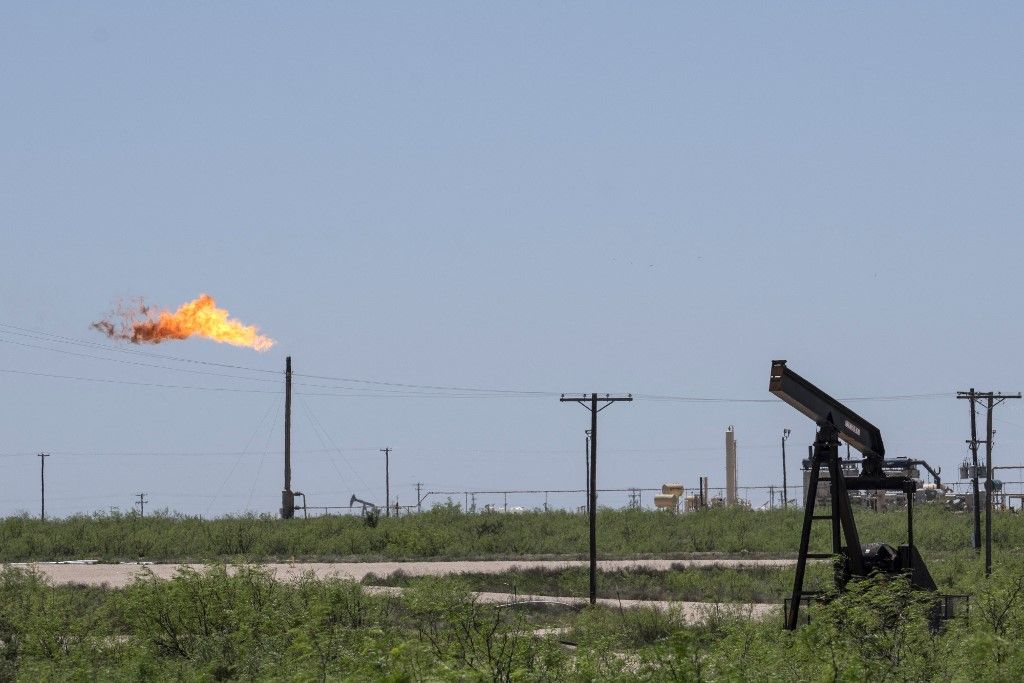 (FILES) A flare stack and pump jacks and other oil and gas infrastructure at the Permian Basin on April 24, 2020, near Odessa, Texas. ExxonMobil sealed a megadeal to acquire Pioneer Natural Resources for about $60 billion, bolstering its holdings in the Permian Basin, a key US petroleum region, the companies announced on October 11, 2023. Under the all-stock transaction, ExxonMobil will buy Texas-based Pioneer for $59.5 billion based on ExxonMobil's closing price on October 5. The overall transaction, including debt, is valued at around $64.5 billion, the companies said. (Photo by Paul Ratje / AFP)