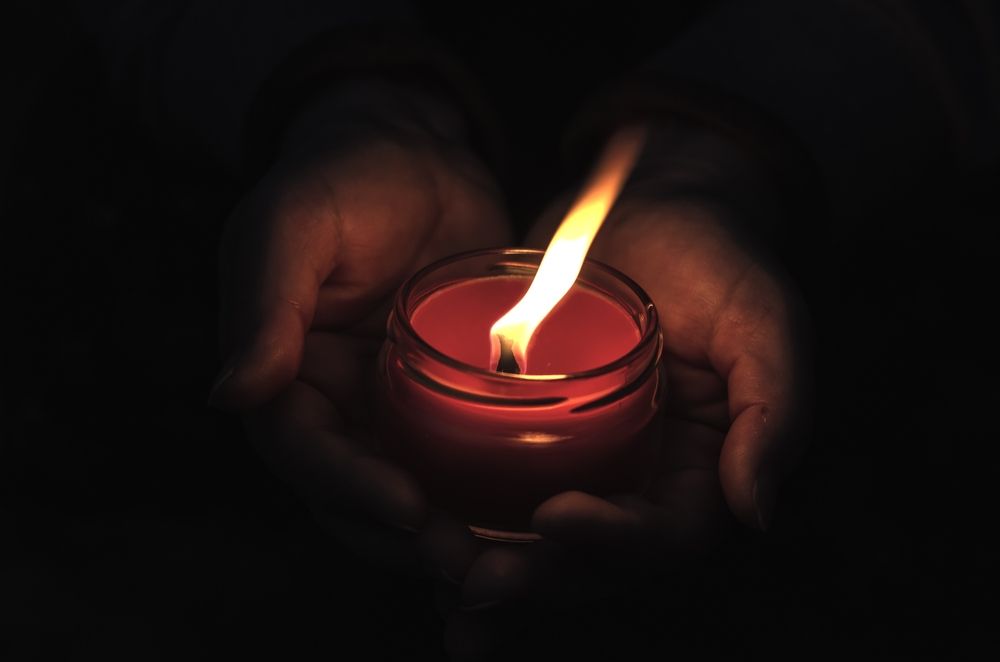 Close-up,Of,Hands,Holding,A,Burning,Candle,In,The,Dark.