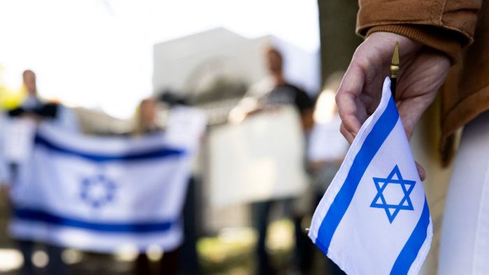 A supporter of Israel holds an Israeli flag in front of the Israeli Embassy in Washington, DC, on October 8, 2023 after the Palestinian militant group Hamas launched an assault on Israel. Israel, reeling from the deadliest attack on its territory in half a century, formally declared war on Hamas Sunday as the conflict's death toll surged close to 1,000 after the Palestinian militant group launched a massive surprise assault from Gaza. (Photo by Julia Nikhinson / AFP)