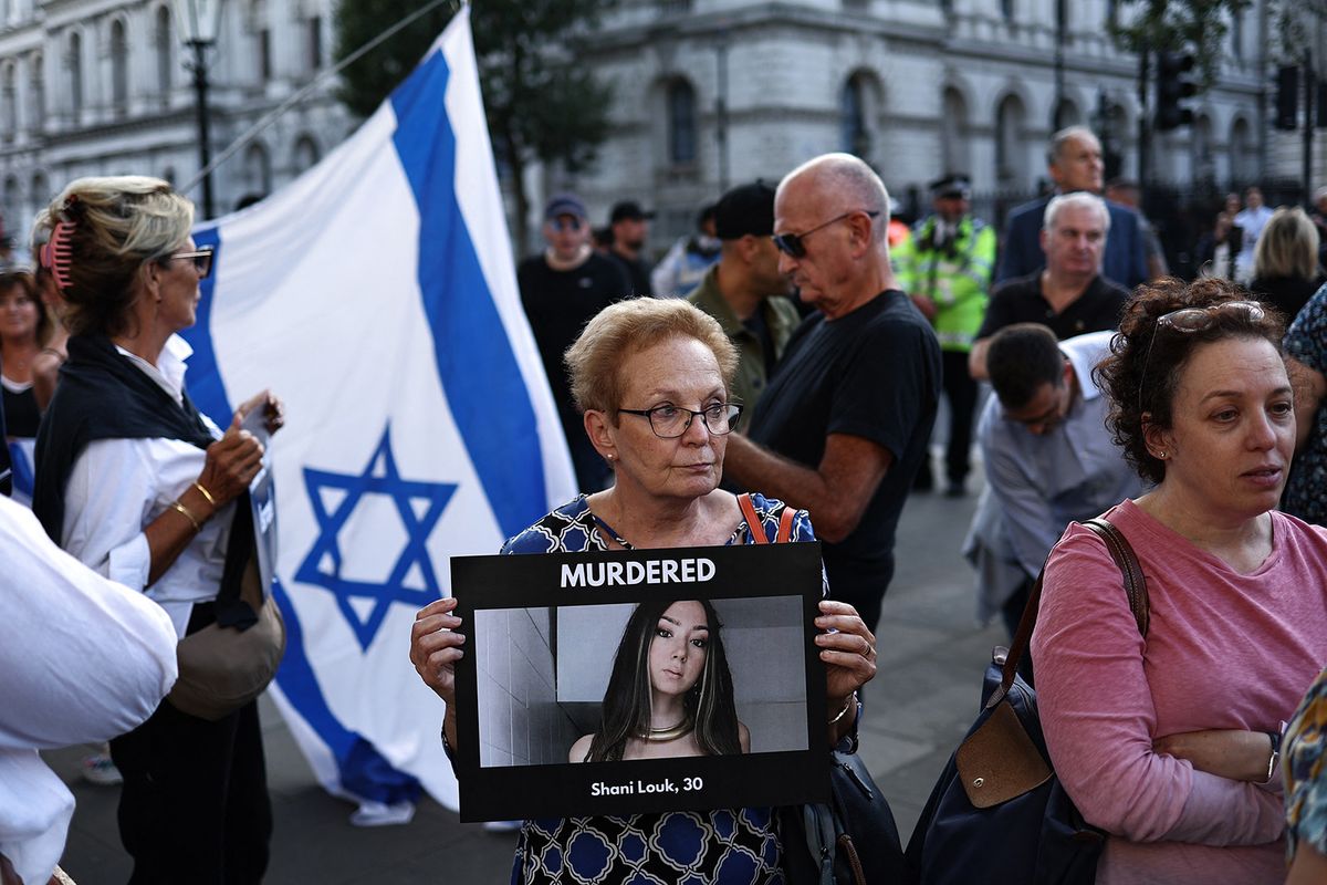 An attendee holds an image of German-Israeli woman Shani Louk, as she takes part in a 'Vigil for Israel' opposite the entrance to Downing Street, the official residence of Britain's Prime Minister, in London on October 9, 2023. (Photo by HENRY NICHOLLS / AFP)