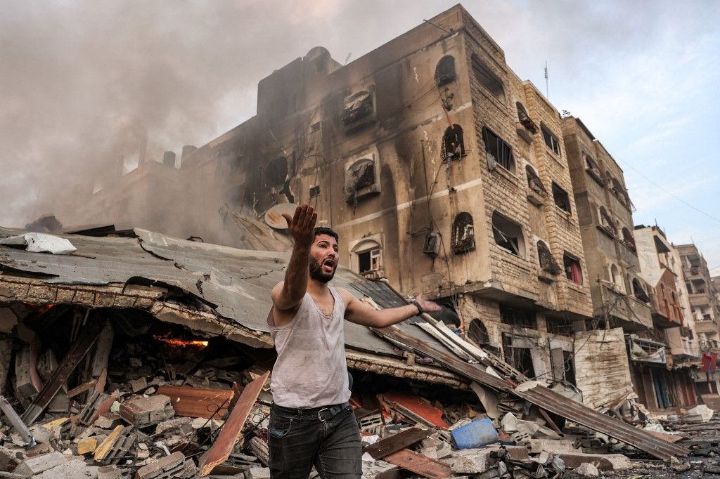 A man reacts outside a burning collapsed building following Israeli bombardment in Gaza City on October 11, 2023. At least 30 people have been killed and hundreds wounded as Israel pounded the Gaza Strip with hundreds of air strikes overnight, a Hamas government official said on October 11. The Israeli military confirmed it had hit several Hamas targets during the night in the Palestinian enclave. (Photo by MOHAMMED ABED / AFP)