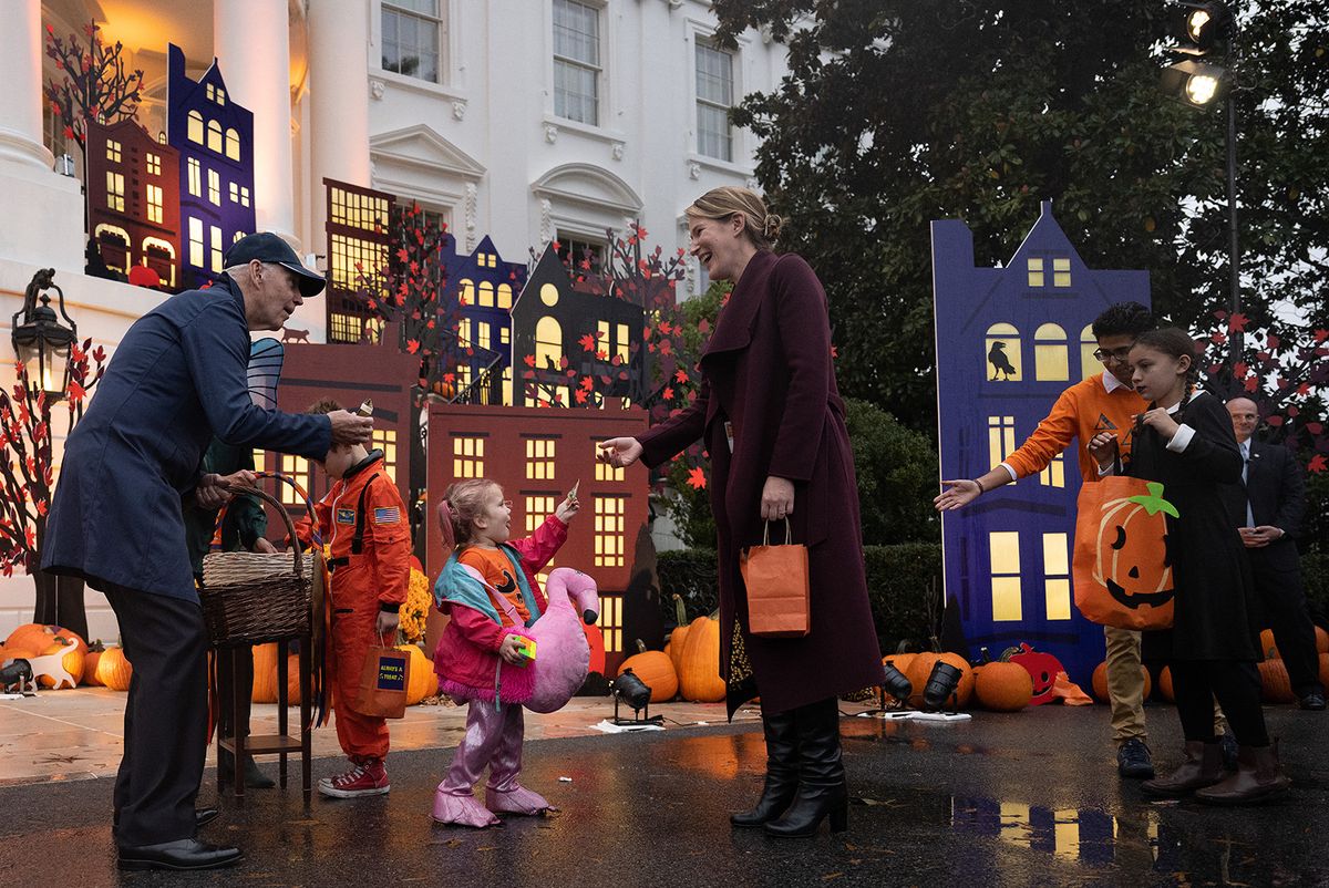 US President Joe Biden (L) hands out candy as he and the First Lady host "Trick-or-Treating in the President and First Lady's Neighborhood" on the South Lawn of the White House in Washington, DC, on October 31, 2022. The President and First Lady are hosting local children of firefighters, nurses, police officers, and members of the National Guard at the White House for trick-or-treating. (Photo by Jim WATSON / AFP)