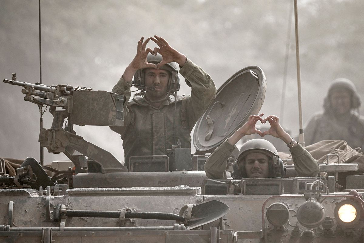 EDITORS NOTE: Graphic content / Israeli soldiers make the heart sign with their fingers as they sit in an in an armored vehicle rolling along the border with the Gaza Strip, in southern Israel on October 13, 2023, as battles between Israel and the Palestinian Hamas movement continue for the seveth consecutive day. Thousands of people, both Israeli and Palestinians have died since October 7, 2023, after Palestinian Hamas militants entered Israel in a surprise attack leading Israel to declare war on Hamas in the Gaza Strip enclave on October 8. (Photo by Aris MESSINIS / AFP)