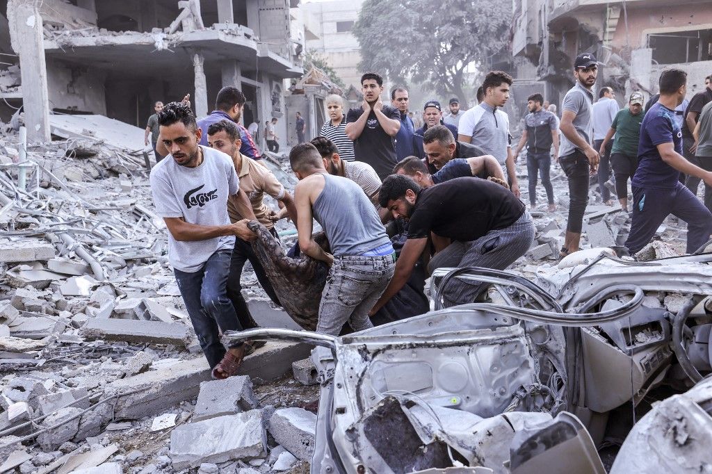 EDITORS NOTE: Graphic content / Palestinians evacuate a victim following an Israeli airstrike on Rafah, in the southern Gaza Strip on October 17, 2023, amid the ongoing battles between Israel and the Palestinian group Hamas. Relief convoys which have been waiting for days in Egypt were on October 17, headed towards the Rafah border crossing with the besieged Palestinian enclave of Gaza, aid officials said, as thousands of people, both Israeli and Palestinians have died since October 7, 2023, after Palestinian Hamas militants based in the Gaza Strip, entered southern Israel in a surprise attack leading Israel to declare war on Hamas in Gaza on October 8. (Photo by MOHAMMED ABED / AFP)