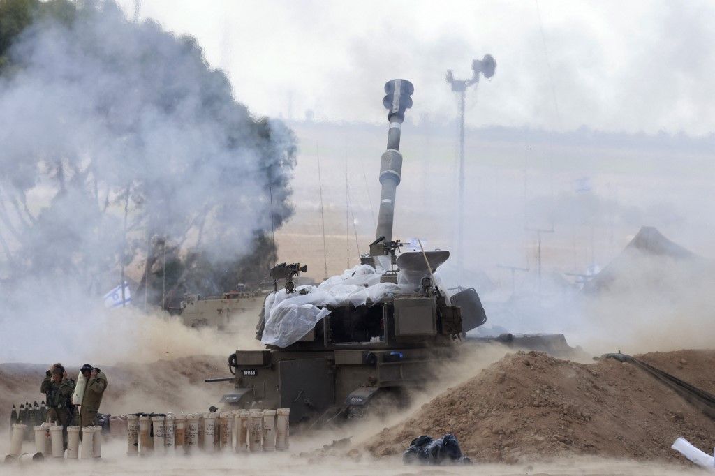 EDITORS NOTE: Graphic content / Israeli soldiers block their ears as a M109 155mm self-propelled howitzer fires rounds from near the Israeli border with Gaza in southern Israel on October 17, 2023, amid the ongoing battles between Israel and the Palestinian group Hamas in the Gaza Strip. Thousands of people, both Israeli and Palestinians have died since October 7, 2023, after Palestinian Hamas militants based in the Gaza Strip, entered southern Israel in a surprise attack leading Israel to declare war on Hamas in Gaza on October 8. (Photo by Menahem KAHANA / AFP)