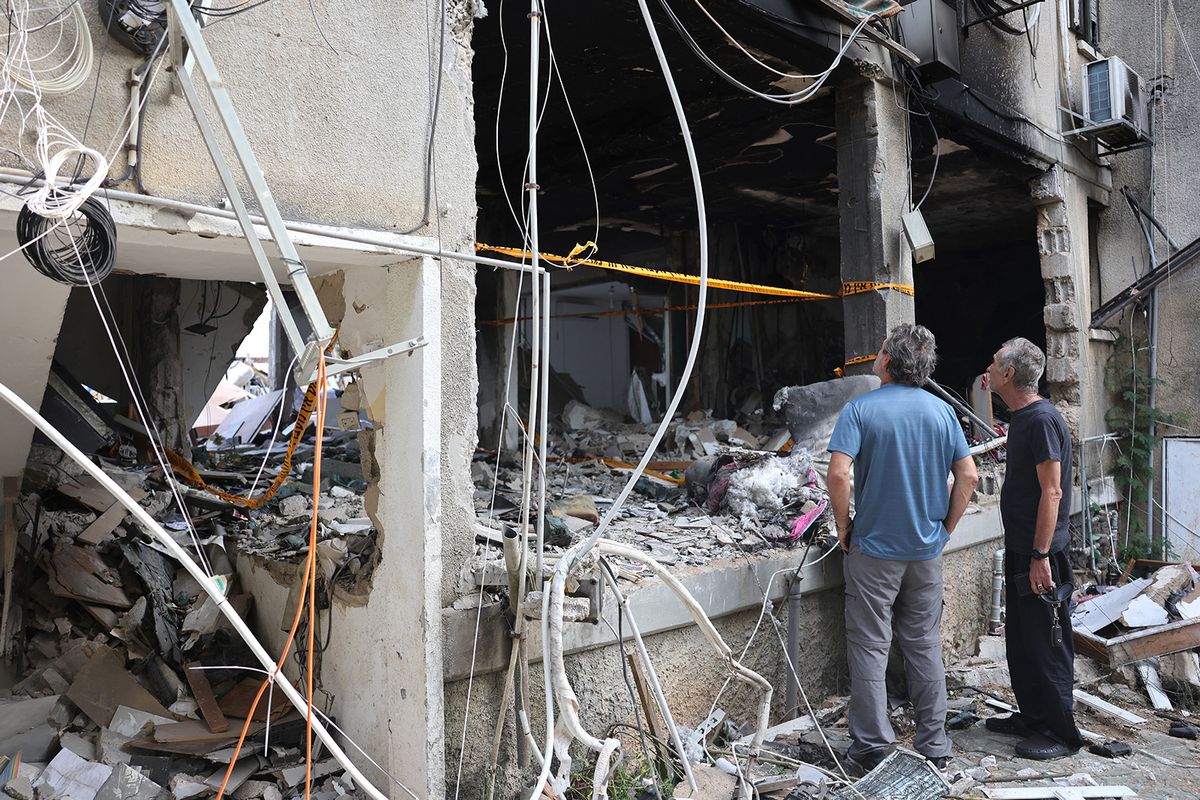 People inspect the damage to a building in the southern city of Ashkelon on October 9, 2023, after it was hit during the night by a rocket from the Gaza Strip. Israel relentlessly pounded the Gaza Strip overnight and into October 9 as fighting with Hamas continued around the Gaza Strip, as the death toll from the war against the Palestinian militants surged above 1,100. (Photo by Menahem KAHANA / AFP)