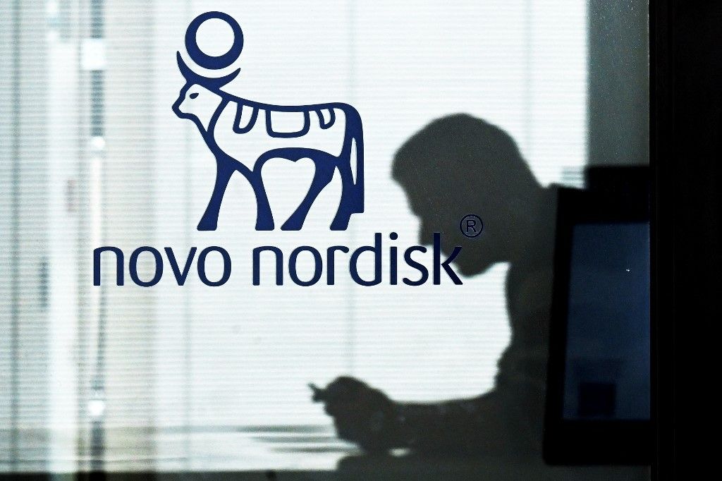  Novo Nordisk An employee sits next to a door bearing the logo of Novo Nordisk at the factory in Hilleroed on September 26, 2023. Novo Nordisk is a leading global healthcare company, founded in 1923 and headquartered in Denmark, aiming to defeat diabetes and other serious chronic diseases such as obesity and rare blood and endocrine disorders. On June 12, 2023, the company announced plans to invest 15.9 billion Danish kroner to expand an existing Active Pharmaceutical Ingredient (API) production facility in the country. (Photo by Sergei GAPON / AFP)