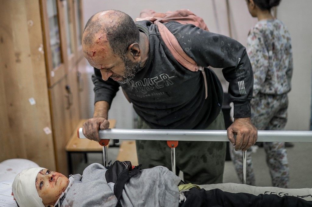 An injured Palestinian man looks at an injured child lying on a gurney at the hospital following the Israeli bombardment of Khan Yunis in the southern Gaza Strip on November 15, 2023, amid the ongoing battles between Israel and the Palestinian group Hamas. More than 10,000 people have been killed in relentless Israeli bombardment of the Gaza Strip, according to the Hamas-run health ministry, since the war erupted after Palestinian militants raided southern Israel on October 7 killing at least 1200 people, according to official Israeli figures. (Photo by Belal KHALED / AFP)