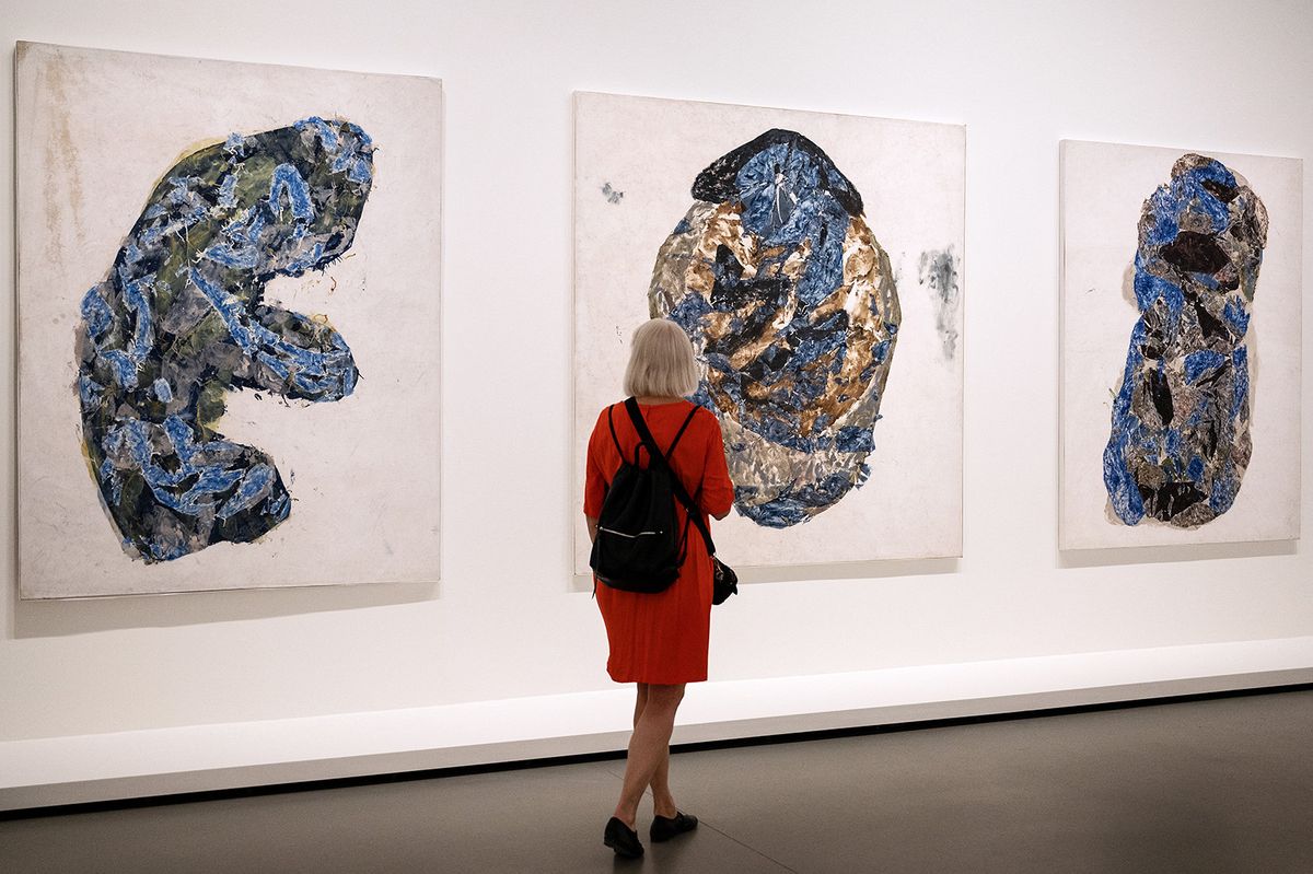 A visitor walks past artworks by Hungarian abstract painter Simon Hantai (1922-2008) during a press visit at the Louis Vuitton Foundation in Paris on May 17, 2022. "Simon Hantai, The Centanary exhibition", which celebrates the centenary of hantai's birth, runs from May 18 to August 29, 2022. (Photo by BERTRAND GUAY / AFP) / RESTRICTED TO EDITORIAL USE - MANDATORY MENTION OF THE ARTIST UPON PUBLICATION - TO ILLUSTRATE THE EVENT AS SPECIFIED IN THE CAPTION