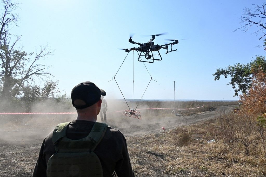 An operator of the volunteer organization 'Postup' controls the flight of an UAV carrying a metal detector to search for mines near the town of Derhachi, Kharkiv region, on October 1, 2023. (Photo by SERGEY BOBOK / AFP)