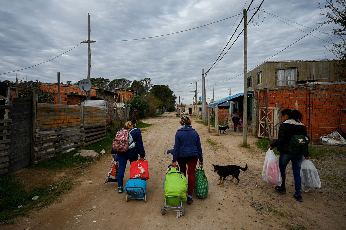 Limpia Benitez (C), a 59-year-old housewife, and Gladys Meza (L), a 41-year-old unemployed woman, walk to their houses with carts full of food in good condition taken from the garbage in Gonzalez Catan, Buenos Aires province, on June 9, 2023. With trained hands and eyes, Limpia Benitez and Gladys Meza pull kilos and kilos of fruit and vegetables from the large bins at the Central Market in Buenos Aires. Neighbors on the outskirts of Buenos Aires, these two women have been traveling 20 kilometers by train and bus every week for the past two years with their shopping trolley and two bags each. It’s a tiresome task, but it's the only way they have to make ends meet in a country with monstrous inflation, which has accumulated 114% in the last 12 months. Argentina has one of the highest inflation rates in the world (114% annualized), and food is one of the items with the highest increase, 117% from June 2022 to May 2023, according to official figures. (Photo by LUIS ROBAYO / AFP)