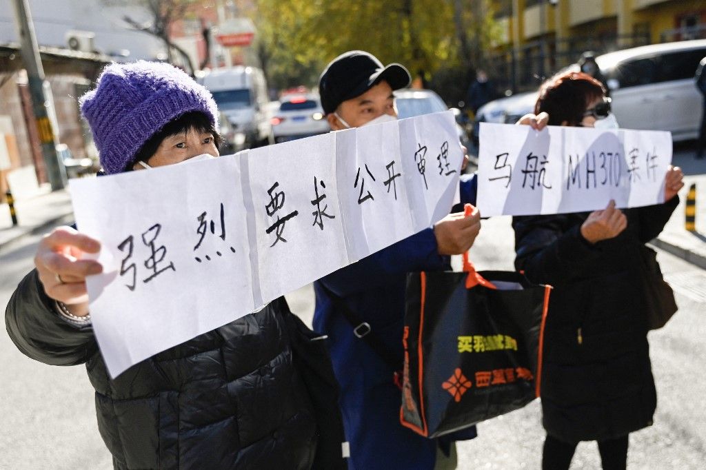 Relatives of passengers of the missing Malaysia Airlines flight MH370 hold a sign reading "We Strongly demand a public trial of the Malaysia Airlines MH370 cases" close to a court building in Beijing on November 27, 2023. A Beijing court on November 27 began hearing compensation cases filed by the families of dozens of Chinese people who died on board a Malaysia Airlines flight that disappeared almost 10 years ago. (Photo by Pedro PARDO / AFP)