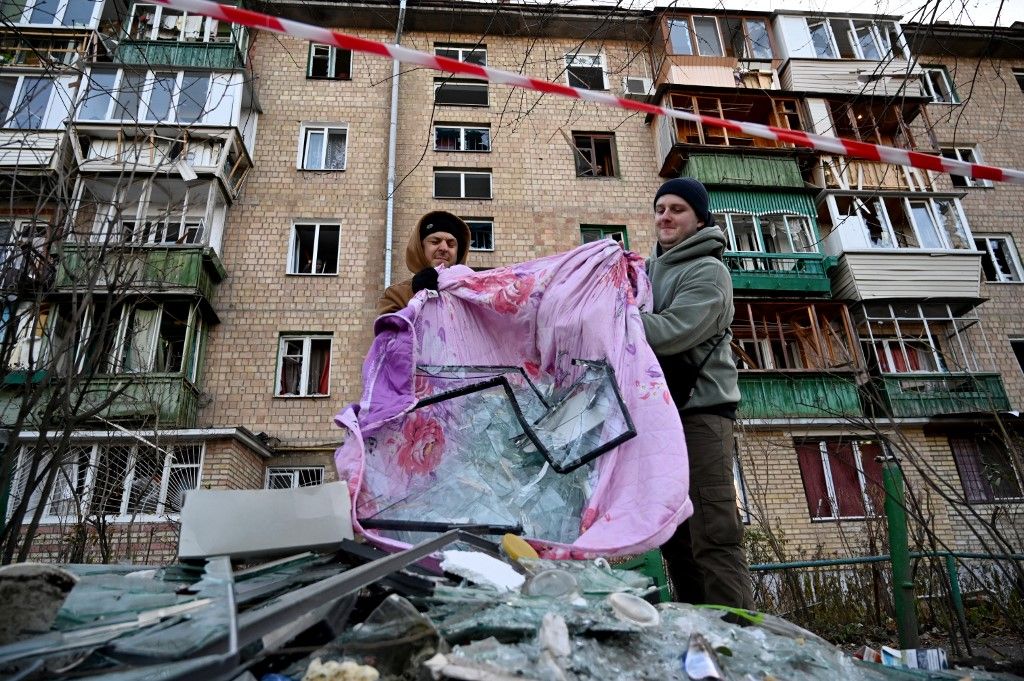 Inhabitants collect broken windows glass after the explosion of a downed Russian drone in a yard among residential buildings in Kyiv on November 25, 2023, amid the Russian invasion of Ukraine. Ukraine said it had downed 71 Russian attack drones overnight in what Kyiv authorities said was the biggest attack on the capital since the start of the invasion. (Photo by Sergei SUPINSKY / AFP)