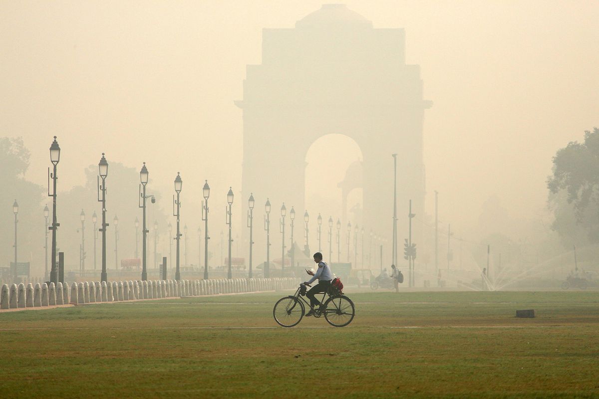 A man cycles past the Kartavya Path in front of the India Gate amid heavy smoggy conditions in New Delhi on November 7, 2023. Air quality in the national capital has plummeted to the severe category in the past few days. The air pollution in Delhi typically reaches its peak from November 1 to 15 due to the emissions from vehicles and industries, stubble burning in nearby states, and unfavourable meteorological conditions, such as a drop in temperature and low wind speeds. (Photo by Mayank Makhija/NurPhoto) (Photo by Mayank Makhija / NurPhoto / NurPhoto via AFP)