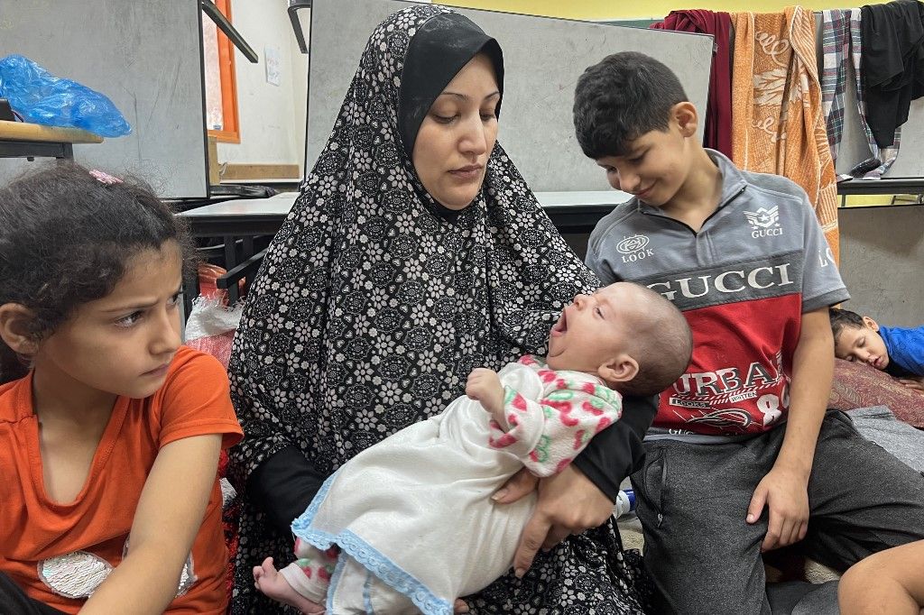 Fadwa Kullab carries her newborn Mohammad at a United Nations Relief and Works Agency for Palestine Refugees in the Near East (UNRWA) school in Rafah in the southern Gaza Strip, on November 10, 2023, where internally displaced Palestinians have taken refuge amid ongoing battles between Israel and the Palestinian militant group Hamas. (Photo by Mai YAGHI / AFP)