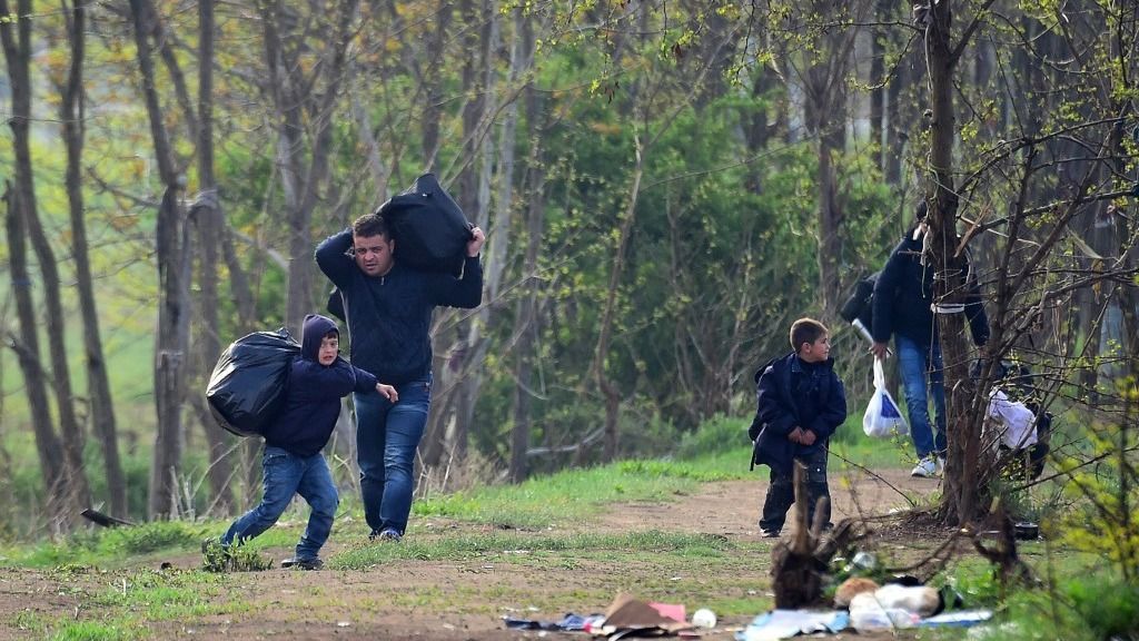 A Syrian family carry their belongings through the forest near the Hungarian border fence at the Tompa border station transit zone on April 6, 2017 as the Hungarian Interior Minister Sandor Pinter (not pictured) presents the camp to the media. The migrant transit complex on the Hungarian side of the border has been expanded to become one of two new detention centers for asylum seekers in the Hungarian transit zone and contains shipping containers that are used to automatically detain migrants in the transit zone while their claims are investigated. (Photo by ATTILA KISBENEDEK / AFP)