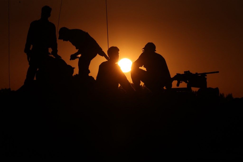 Israeli soldiers stand on the turret of a tank deployed on the southern border with the Gaza Strip on November 29, 2023, as a truce between Israel and Hamas entered a sixth day after a deal was extended to allow further releases of Israeli hostages and Palestinian prisoners. A current truce is scheduled to expire early on November 30, after a six-day pause in a conflict sparked by deadly Hamas attacks that prompted a devastating Israeli military offensive in the Gaza Strip. (Photo by Menahem KAHANA / AFP)