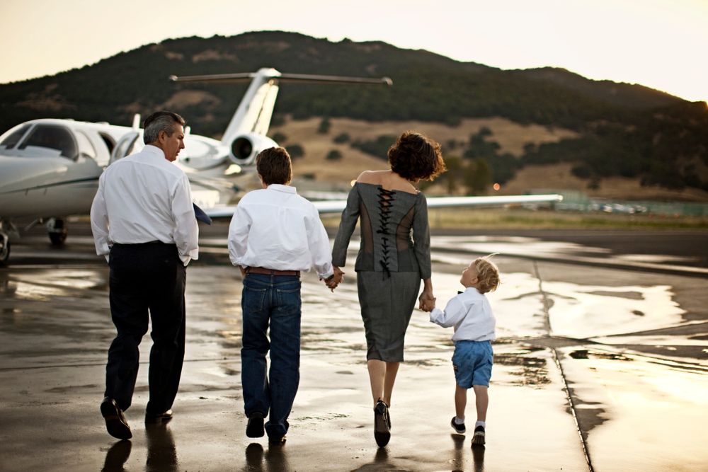 Family,Walking,Towards,A,Private,Jet,Holding,Hands