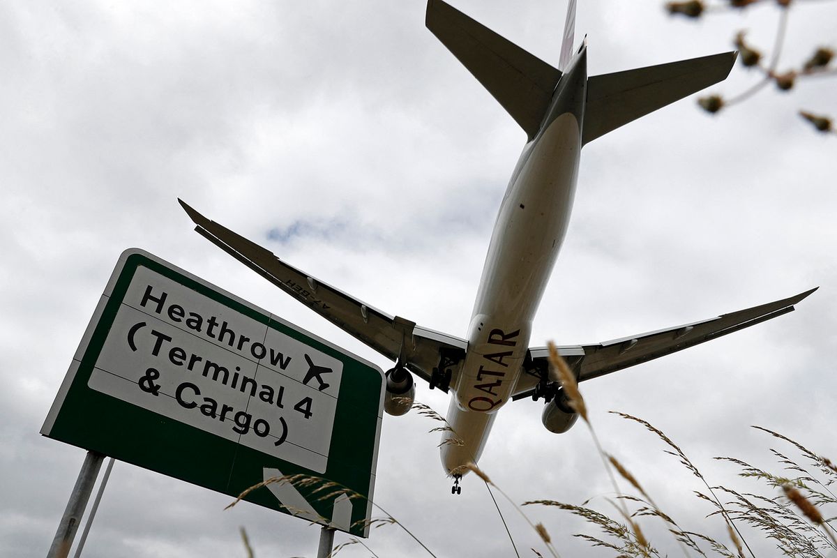 (FILES) A Qatar Airways flight pases above a road sign as it prepares to land at Heathrow airport in west London on June 8, 2020. Spanish infrastructure giant Ferrovial announced it is offloading its remaining 25 percent stake in London's Heathrow Airport to a French private equity group and Saudi Arabia's sovereign wealth fund. After owning the UK travel hub for 17 years, Ferrovial said on November 29, 2023, it had reached a 2.37 billion pound ($3.01 billion) deal with Paris-based Ardian and Riyahd's Public Investment Fund (PIF). (Photo by Adrian DENNIS / AFP), 
brit gazdaság, 