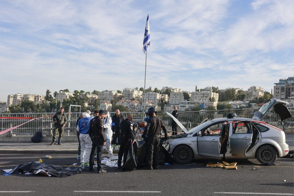 Israeli police and security forces stand next to the covered bodies of suspected attackers as they secure the site of a shooting in Jerusalem on November 30, 2023. (Photo by Menahem KAHANA / AFP)