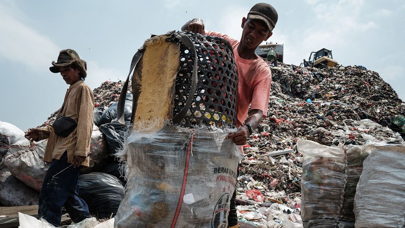 This picture taken on September 14, 2023 shows a registered scavenger, who mainly collects plastic waste to sell, transferring waste from his basket into a sack at the Bantar Gebang landfill, which is the size of 200 football pitches and receives 7,500 tonnes of waste from Jakarta every day, in Bekasi, on the outskirts of Jakarta. Home to around 30 million people, the sprawling megalopolis of Jakarta is facing a trash crisis with its main Bantar Gebang dump site, one of the world's biggest, close to capacity. (Photo by Yasuyoshi CHIBA / AFP) / TO GO WITH Indonesia-environment-waste, PHOTO ESSAY