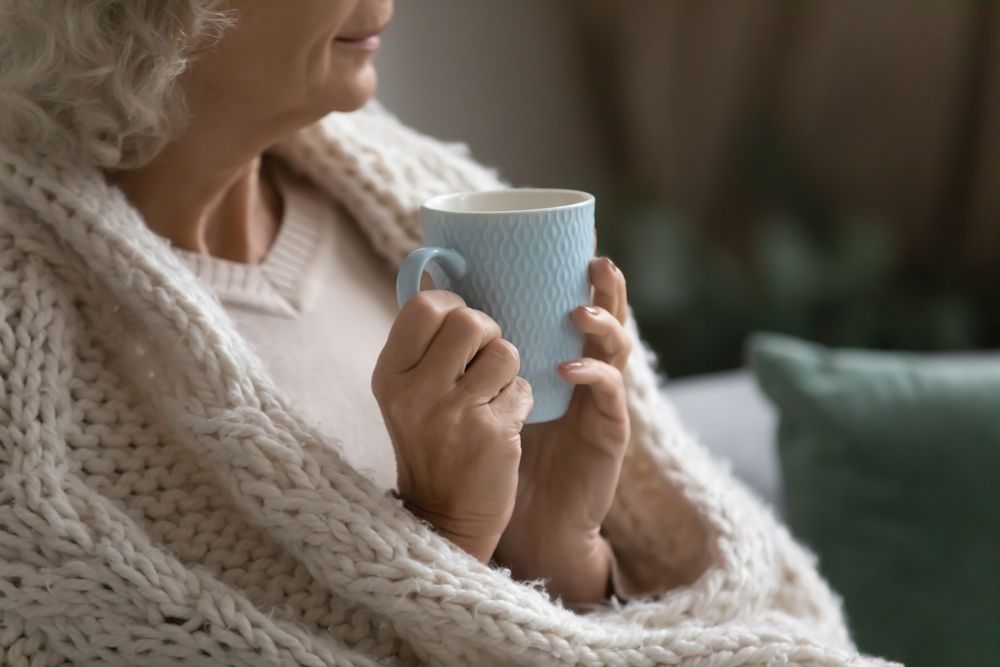 Aged,Calm,Woman,Resting,Wrapped,In,Knitted,Plaid,Drink,Evening