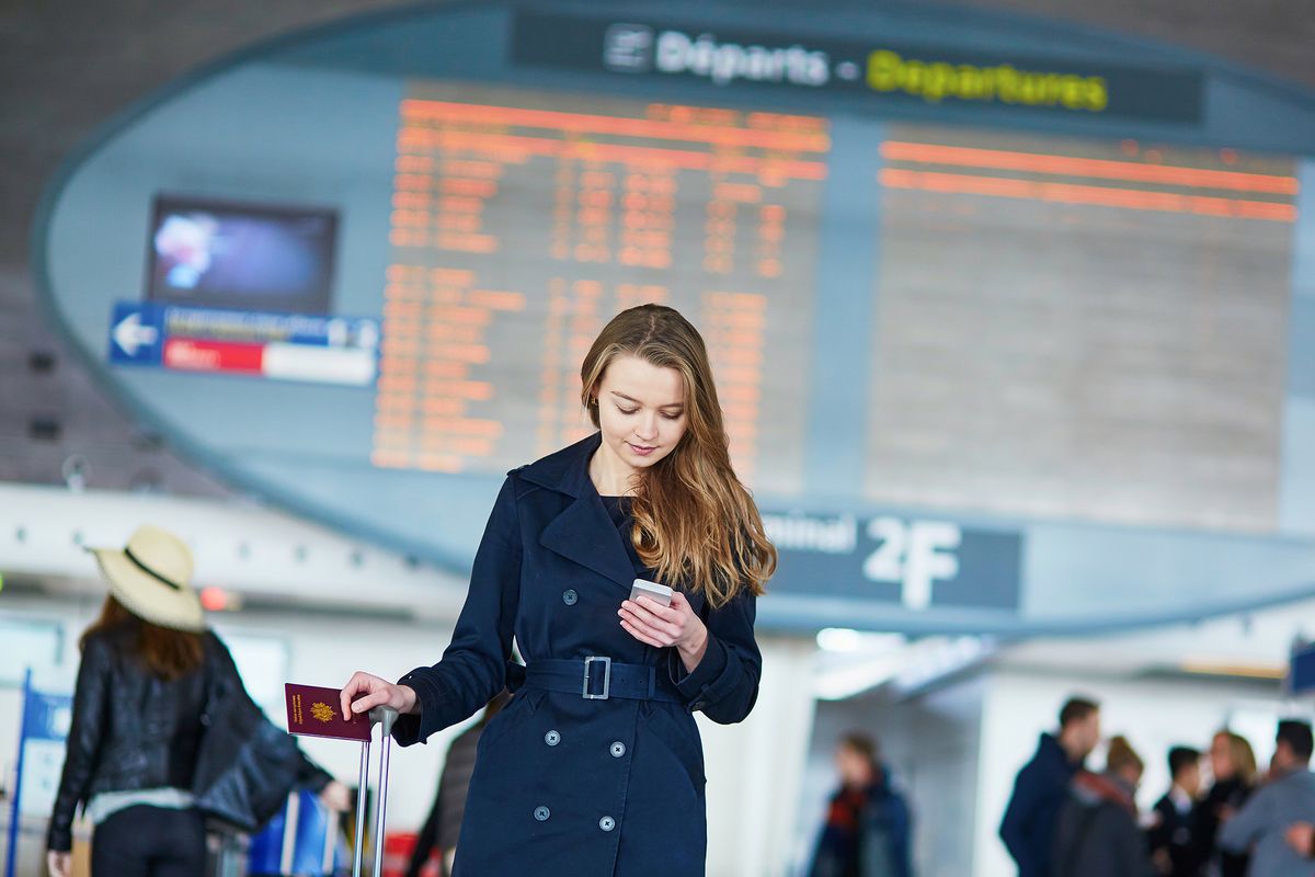 Young,Woman,In,International,Airport,Near,The,Flight,Information,Board,