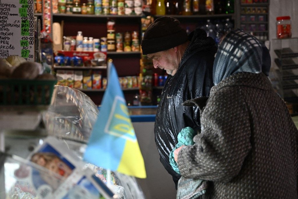 Local residents buy groceries at a small store in the town of Chasiv Yar, near Bakhmut, Donetsk region on March 30, 2023, amid the Russian invasion of Ukraine. The shop on the corner of a muddy road is one of the few remaining open in the heavily shelled town of Chasiv Yar near the frontline in east Ukraine. (Photo by Genya SAVILOV / AFP)